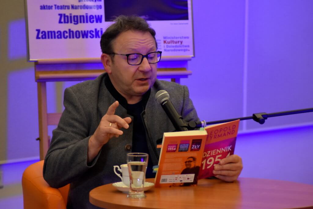 Osoba trzyma w&nbsp;dłoni książkę. Osoba czyta książkę. 