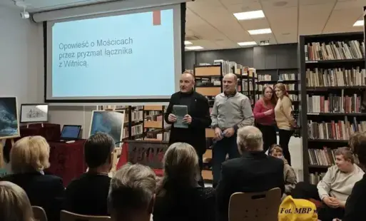 Dwaj mężczyźni stoją przed siedzącymi słuchaczami.