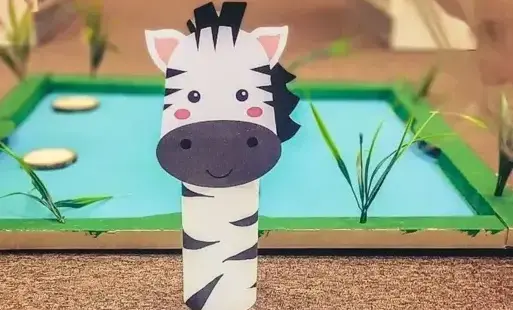 Papierowa zebra z młodymi zebrami przy stawiku.