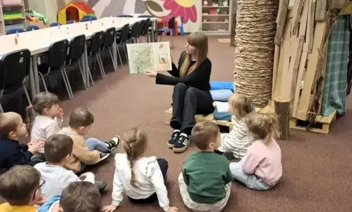 Tytułowe. Pani Bibliotekarka czyta książkę przedszkolakom. 
