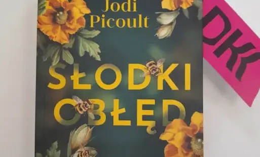 Zdjęcie tytułowe: na białym tle pokazana jest tytułowa książka „Słodki obłęd”. W prawym górnym rogu książki umieszczona jest zakładka w kolorze różowym z czarnym napisem: Dobre książki i kawa po jednej stronie okładki,  DKK po drugiej stronie zakładki.