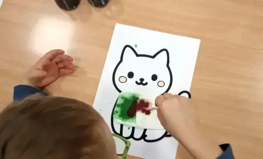 Chłopiec koloruje kotka. 