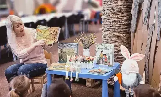 Tytułowe: Bibliotekarka czyta dzieciom książkę o wiośnie.