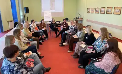 Bibliotekarki oraz trenerki siedzą w kręgu podczas szkolenia.