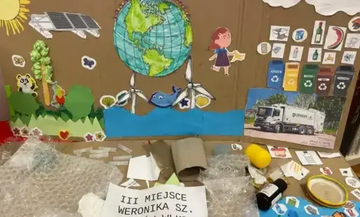 Praca przestrzenna, wyklejanka: kosze na odpady, śmieciarka, ocean i ferma wiatrowa, las i zwierzęta. U podstawny leżą odpady: folie, papiery, plastikowe elementy, butelka, nakrętka od słoika.