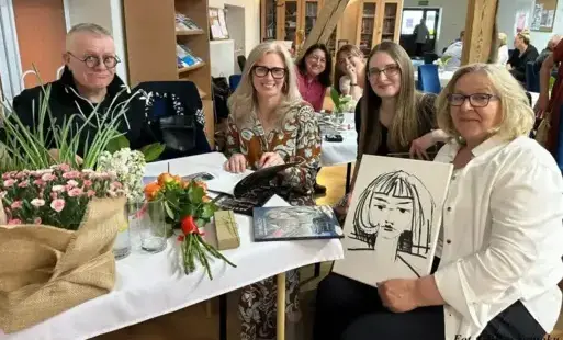 Trzy kobiety i mężczyzna siedzą przy stoliku.