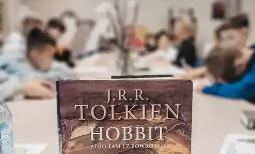 Uczniowie siedzą przy stołach i rozwiązują krzyżówkę inspirowaną lekturą „Hobbit”.
