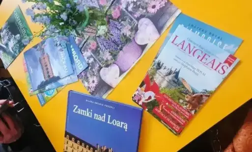 Tytułowe, na stole leżą albumy i ulotki reklamujące zamki nad Loarą