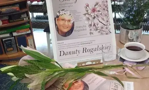 Na zdjęciu widoczny plakat spotkania z autorką i książki ułożone na stoliku.