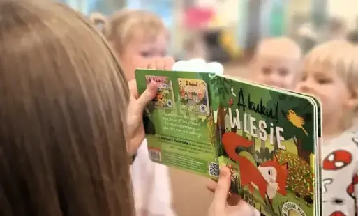 Tytułowe. Bibliotekarka czyta dzieciom książkę. 