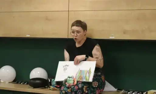 Kobieta siedzi na blacie trzymając w rękach otwartą książkę.