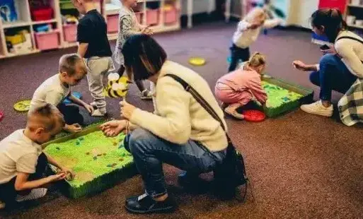 Dzieci wybierają z kolorowego ryżu motylki z makaronu.