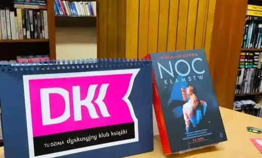 Okładka książki na stole oraz logo DKK