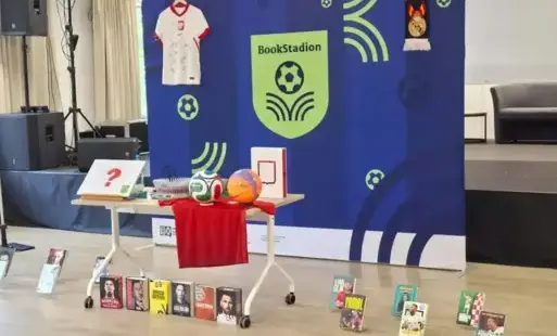 Stoisko promujące literaturę sportową, udekorowane piłkarskimi gadżetami, koszulką oraz książkami o znanych piłkarzach.