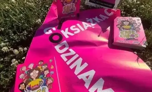 na trawie leży plakat zatytułowany godzinami o książkach a na nim ułożone są książki