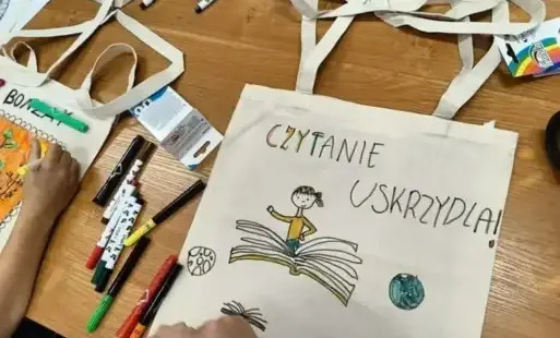 Dzieci ozdabiają materiałowe torby za pomocą kolorowych flamastrów