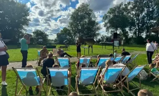 Grupa ludzi siedzących na leżakach podczas plenerowego spotkania.