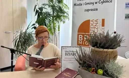 Kobieta czyta książkę do mikrofonu.
