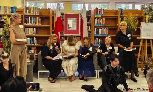 Osoby siedzą na kanapie w bibliotece i  wspólnie czytają książki.