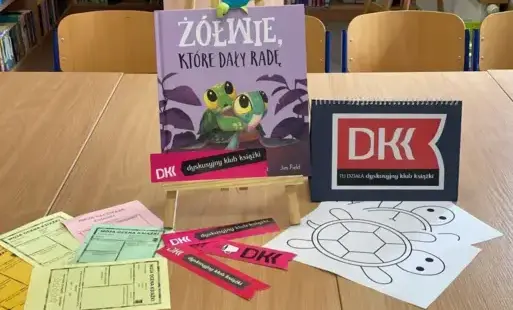 Zdjęcie startowe – przedstawia książkę autorstwa Rachel Bright oraz Jim Field „Żółwie, które dały radę”, napis DKK, zakładki DKK oraz materiały do wykonania pracy plastycznej.