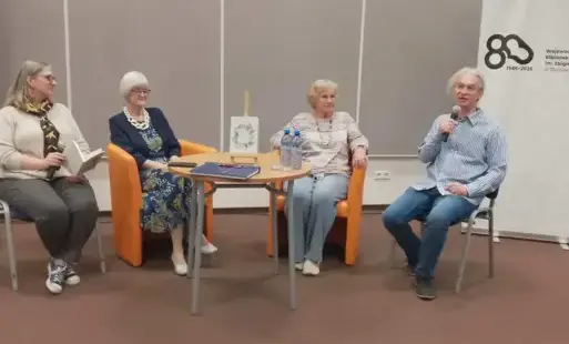 cztery osoby przy stoliku rozmawiają, z boku baner Biblioteki Herberta