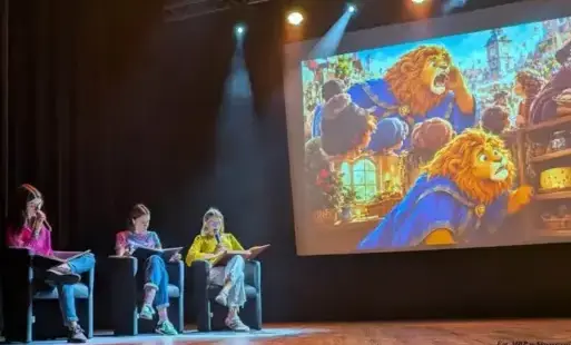 Trzy kobiety siedząc w fotelach na scenie czytają książki.