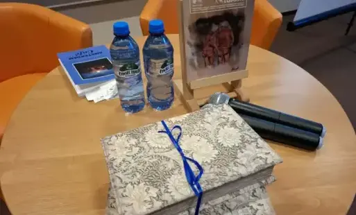 Stolik, na którym znajduje się numer Pegaza, wody, tomik poezji i przewiązane sznurkiem szkatułki