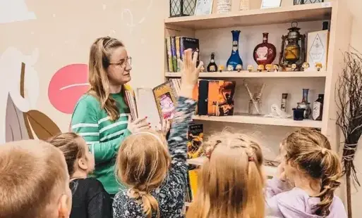 Tytułowe: Bibliotekarka oprowadza dzieci po Oddziale Dziecięcym.