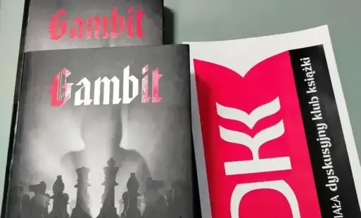 Na zdjęciu są dwa egzemplarze książki Macieja Siembiedy „Gambit”. Jeden leży na drugim. Obok jest naklejka z logiem Dyskusyjnego Klubu Książki.