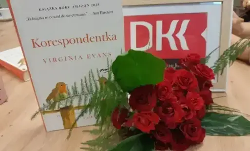 zdjęcie startowe  - omawiana lektura w towarzystwie logo DKK oraz bukietu czerwonych róż.