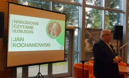 Ekran, na którym prezentowany jest slajd z prezentacji o Janie Kochanowskim, obok, po prawej stronie stoi Dyrektor Biblioteki Sławomir Szenwald