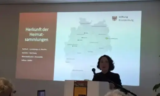 dr Magdalena Kamińska w trakcie wygłaszania referatu, za nią slajd z prezentacji