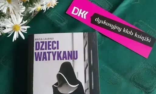 Na ciemno zielonej serwecie książka, fioletowe emblematy Dyskusyjnego Klubu Książki, bukiet jasnych kwiatów.