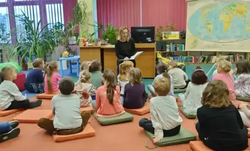 Dzieci siedzą na dywanie na wprost bibliotekarki i biorą udział w pogadance o różnorodności.