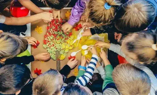 dzieci wsypują kolorowy ryż, makaron oraz fasolkę do drzewka wykonanego z rolek.  