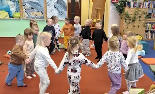 Dzieci tańczą w kółeczku trzymając się za ręce.