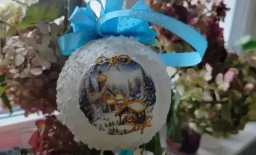 Bombka wykonana na warsztatach na tle hortensji, które stoją na parapecie.