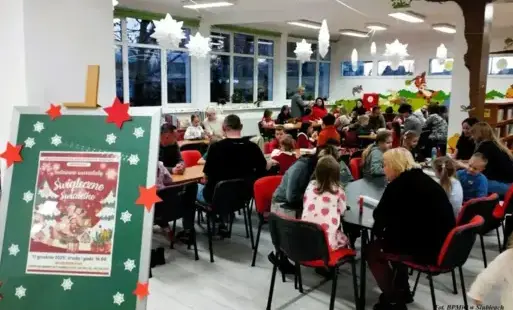 Uczestnicy warsztatów siedzą przy stołach.