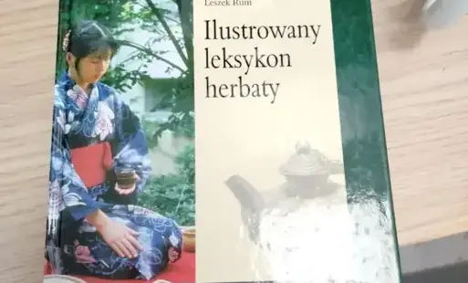 Książka „Ilustrowany leksykon herbaty” Leszka Ruma leży na jasnym blacie.