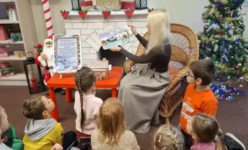 Bibliotekarka czyta dzieciom książkę podczas zimowych zajęć w bibliotece.