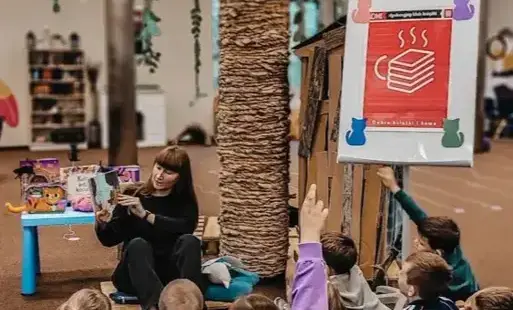 Pani Bibliotekarka czyta przedszkolakom książkę. 
