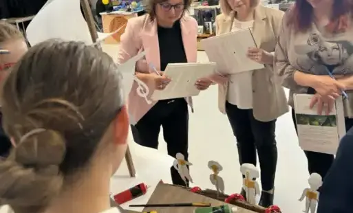 Trzy kobiety przy stoliku z prezentacją.