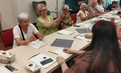 Uczestnicy zebrani przy stole klaszczą lub słuchają wypowiedzi.