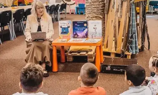 Bibliotekarka rozmawia z dziećmi podczas lekcji bibliotecznej.