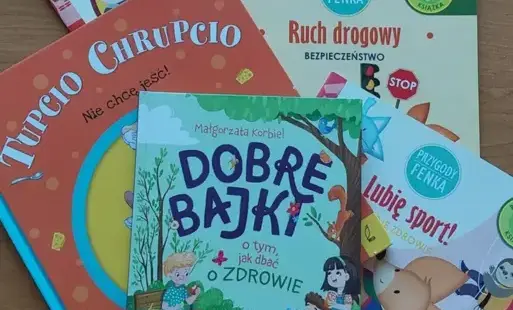 Na jasno brązowym blacie kolorowe książki dziecięce.