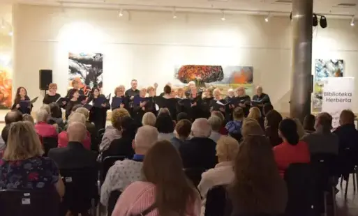 Chór Cantabile występuje na scenie podczas koncertu, a zgromadzona publiczność słucha wykonywanych utworów.