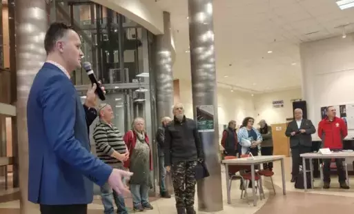 Grzegorz Urbanek przy mikrofonie, w tle autorzy i wydawcy zgromadzeni wokół stoisk