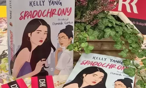 1.	Na stole znajdują się dwie książki „Spadochrony”, zakładki do książek z logo DKK oraz bluszcz z wrzosem w drewnianej skrzyneczce.