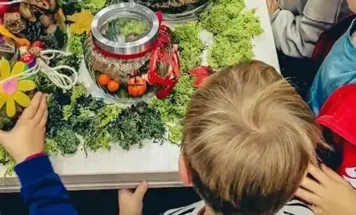 Dzieci oglądają prace prezentujące jesień w słoikach. 