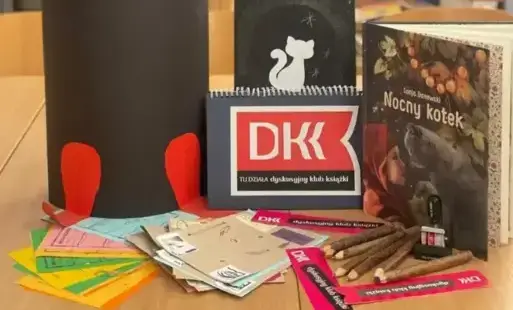Czarny kot z papieru, książka S. Danowski „Nocny Kotek”, napis DKK, zakładki DKK, dzienniczki DKK oraz karty oceny